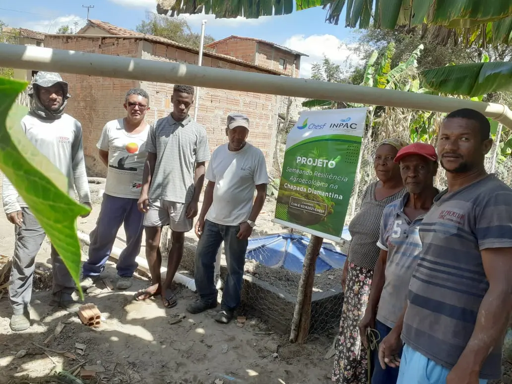 Famílias e equipe técnica reunidas junto a uma fossa ecológica implantada pelo projeto