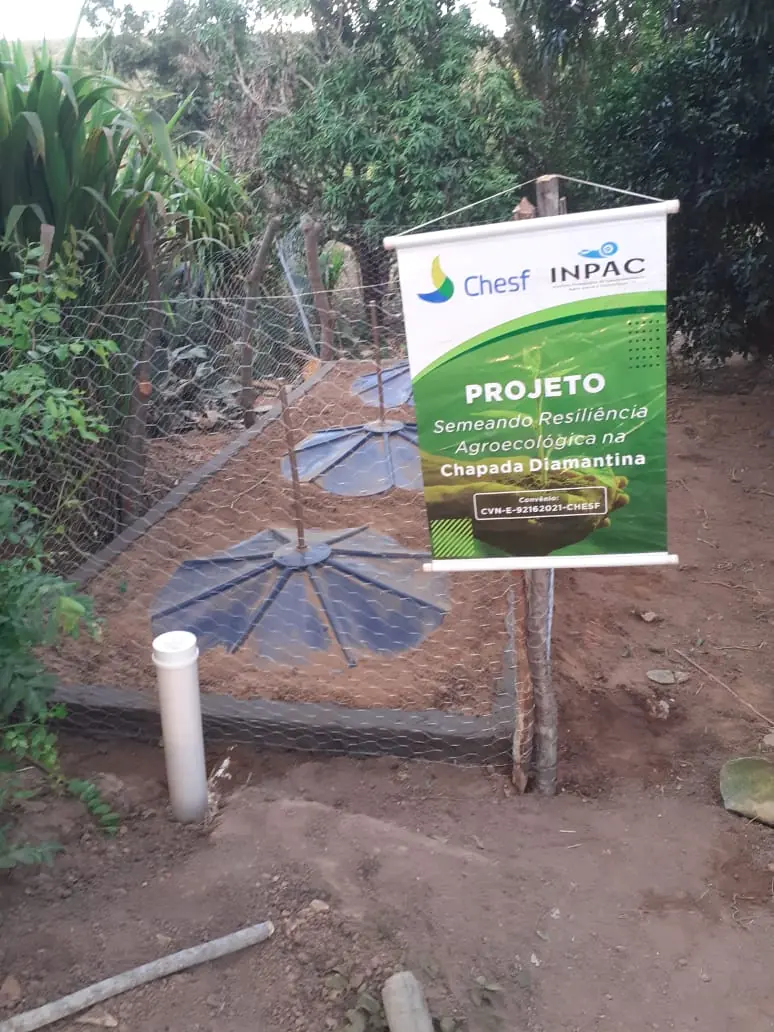 Unidade de fossa ecológica protegida por cerca e acompanhada de placa do projeto